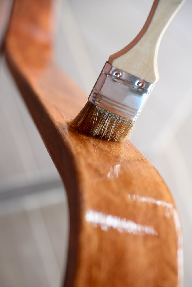 Detalle de brocha barnizando madera de una silla